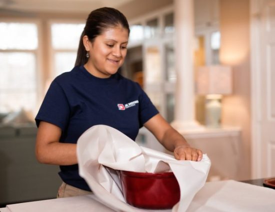 Young Hispanic woman packing kitchenware