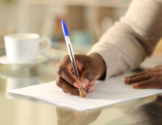 Close up of hands filling out form on a desk