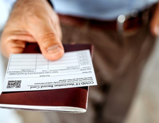 Man handing over passport and vaccine card because he is traveling