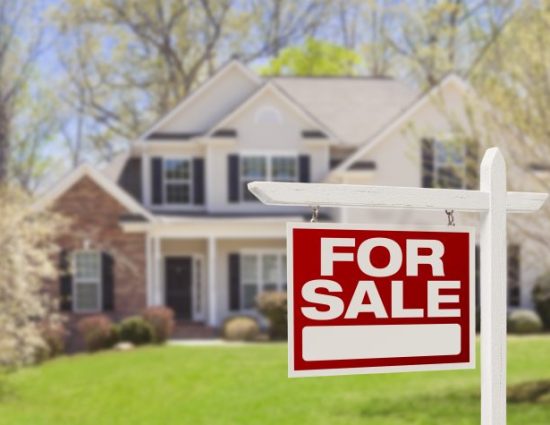 For Sale sign in front of large house