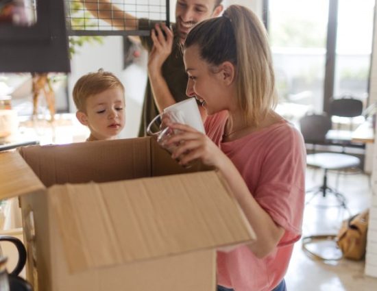 Photo of a young family with a little boy, unpacking essentials in the kitchen of their new home